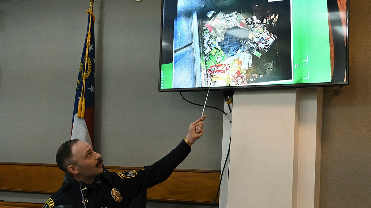 Athens-Clarke County police officer Zachary Davis points out the jacket he collected from a dumpster on photograph as he testifies on the witness stand during a trial of Jose Ibarra