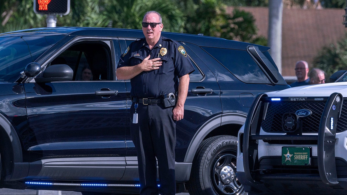 School Police Major J. McCarthy puts his hand on his heart after a motorcade drove by carrying two Palm Beach County Sheriff's Office deputies who were struck and killed by a vehicle