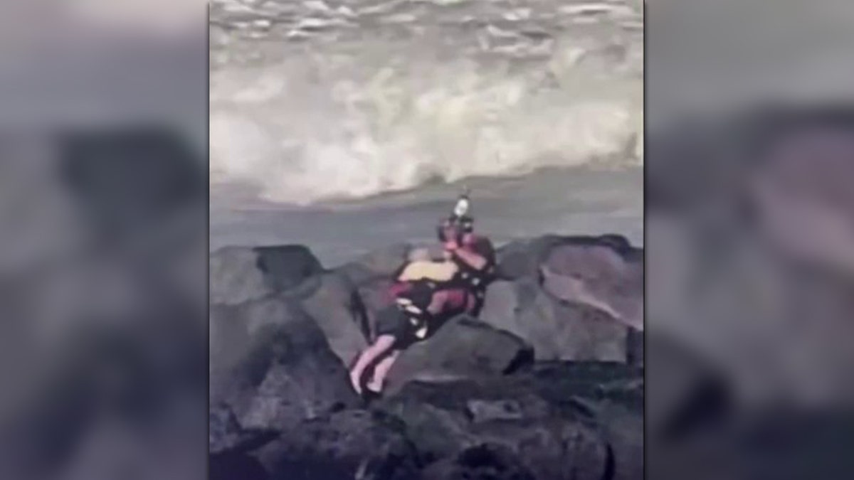 Coast Guard rescuing man from rocks in water