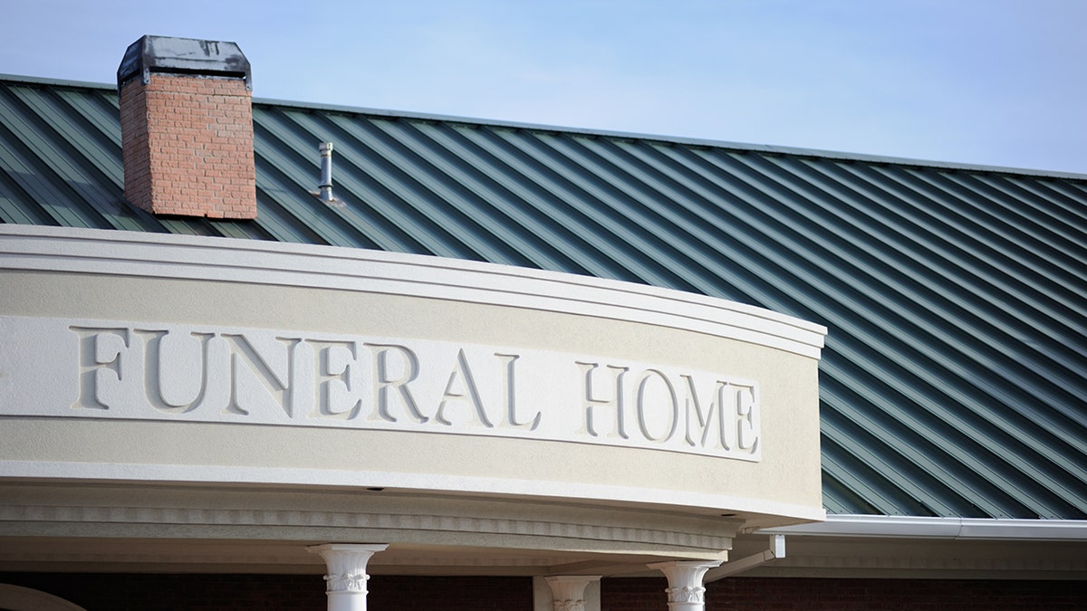 Close up of funeral home sign engraved on curved building front with copy space above