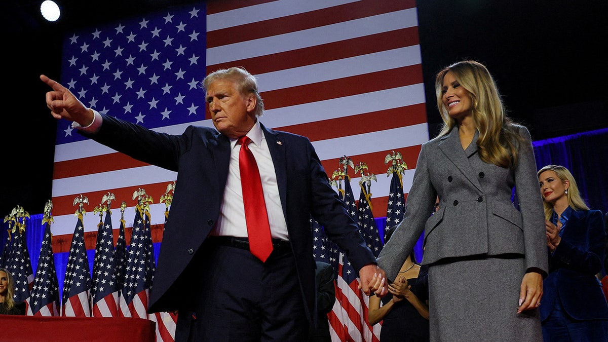 Republican presidential nominee and former President Donald Trump gestures as he holds hands with his wife Melania during his rally at the Palm Beach County Convention Center