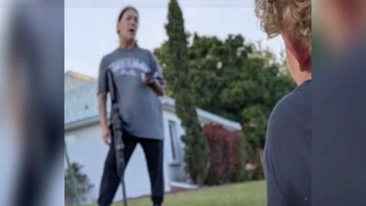 Donna Elkins holds a long pellet gun while wearing a gray t-shirt.